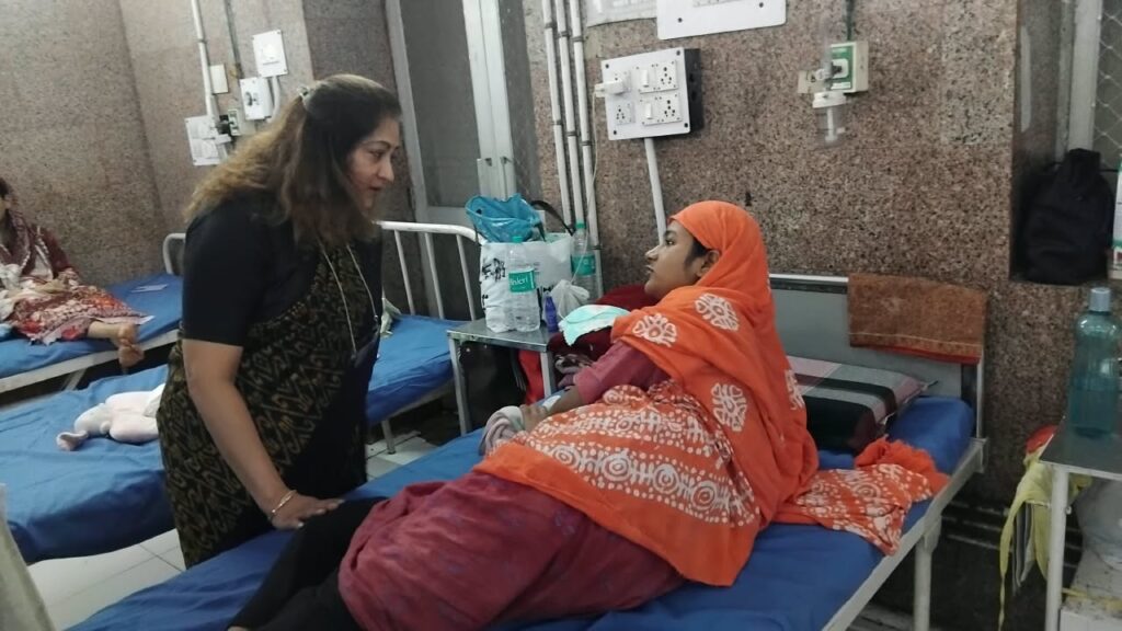 गिरधर लाल अस्पताल के वार्ड में बिस्तर के पास एक महिला मरीज से बातचीत करती हुई महिला।