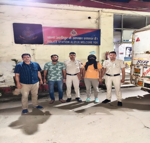 दिल्ली पुलिस की उपलब्ध कराई तस्वीर में अलीपुर थाने के बाहर पुलिसकर्मी और चेहरा ढके एक व्यक्ति।