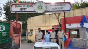 शाहबाद डेरी में हथियार के साथ गिरफ्तारी से लूट केस का सुराग; नकदी और पहचान दस्तावेज बरामद शाहबाद डेरी थाने के बाहर बरामद सामान और चेहरा ढके आरोपी के साथ पुलिस अधिकारी
