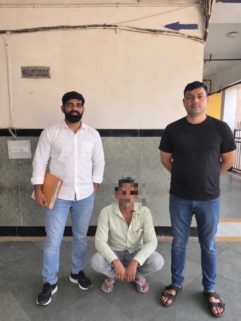 पकड़े गए व्यक्ति के साथ दिल्ली पुलिस के कर्मी; उपलब्ध कराए गए चित्र में उसका चेहरा धुंधला है