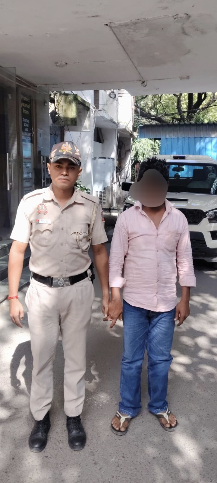 एटीएम ठगी मामले की तस्वीर में दिल्ली पुलिस अधिकारी और ढके चेहरे वाला व्यक्ति