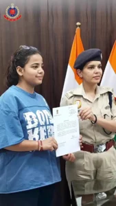 शालीमार बाग मेट्रो के पास फोन छीनने वालों का स्कूटी से पीछा कर पकड़वाया, युवती सम्मानित दिल्ली पुलिस के शालीमार बाग वीडियो के स्थिर दृश्य में दस्तावेज थामे युवती और पुलिस अधिकारी